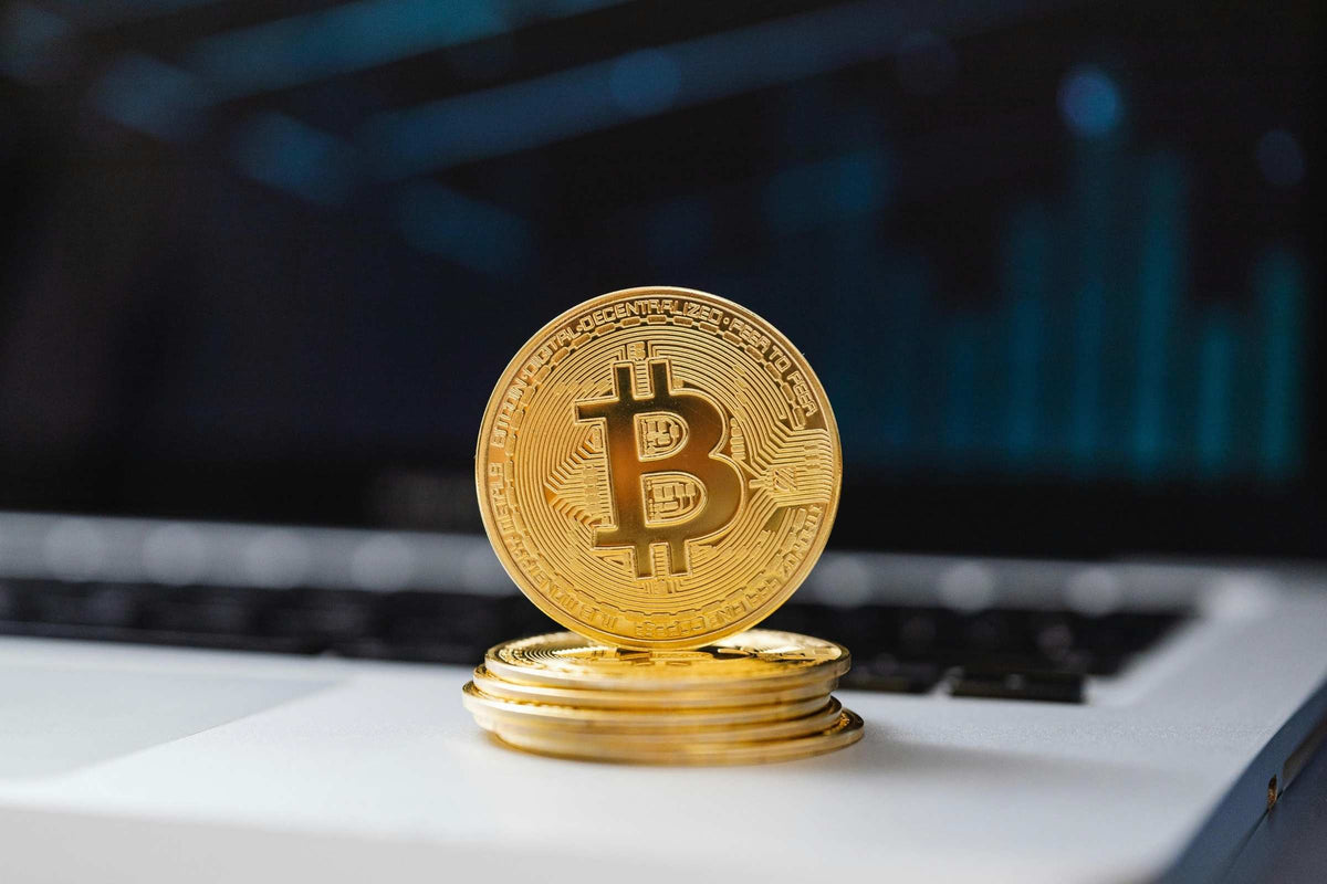 Stack of gold Bitcoin coins on a laptop with a blurred background